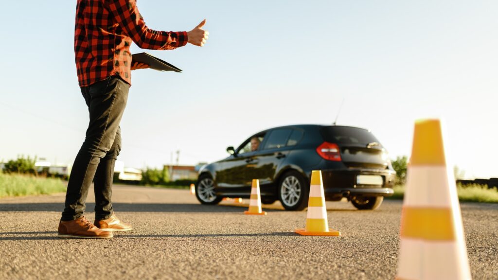 Der Ausbilder hilft dem Schüler beim Fahren zwischen den Kegeln