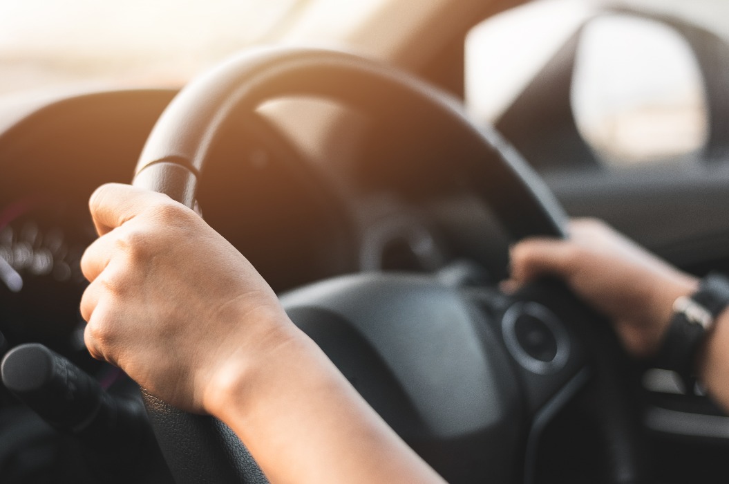 Unscharfes Bild einer Frau, die das Lenkrad hält, um ein Auto für die Führerscheinprüfung in der Schule zu fahren - Transportkonzept